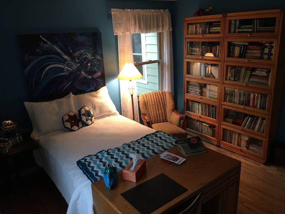Cozy queen-size bed, reading chair, and bookshelves.