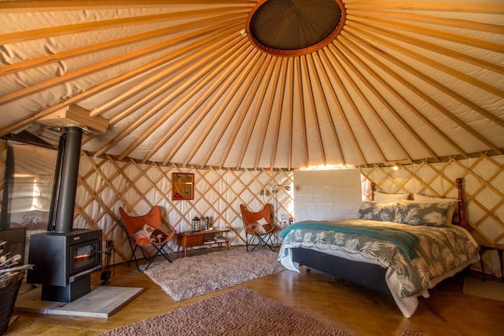 Inside yurt -fireplace chairs and queen sized bed