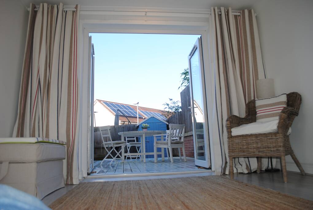 Doors leading to private decking seating dinning area with barbecue.