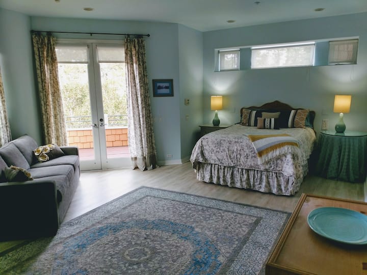 جناح غرفة نوم رئيسي مع سطح خاص وإطلالة على الغابة.