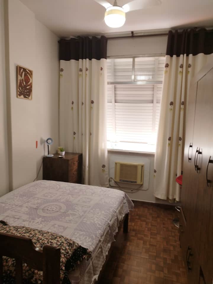 Cómoda cama con colchón ortopédico nuevo, dentro del armario hay ropa de cama, bañera y plancha, la tabla de planchar está apoyada contra el armario 