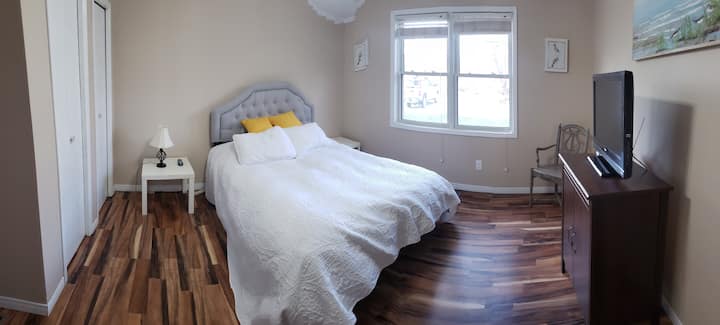 Main floor bedroom with 2 end tables, lamp, queen bed with double closet and ceiling fan.