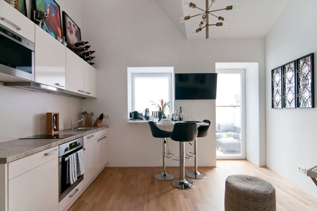 Kitchenette to the left with the breakfast bar and the access to a private small terrace with lounge furniture.