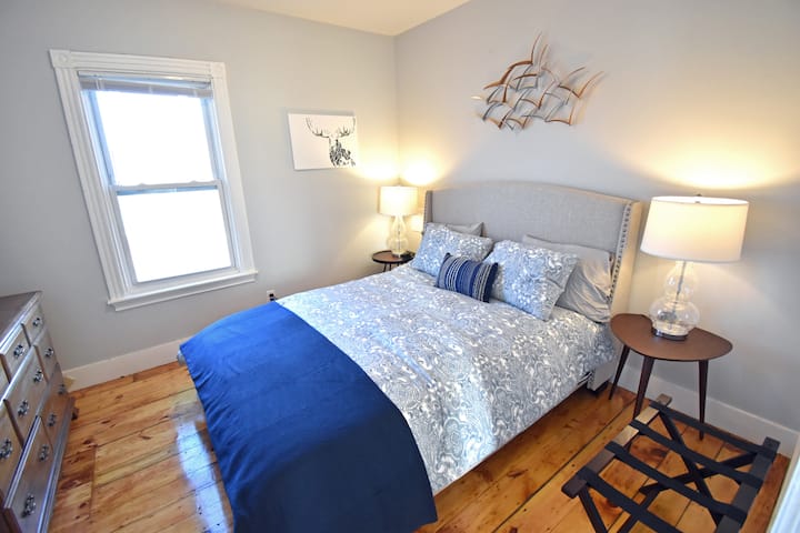 Justo al lado de la sala de estar, otro dormitorio privado cuenta con una cama tamaño queen con colchón de espuma de alta gama de Wayfair, edredón de plumas y cargadores para tu teléfono (dos puertos USB, más un enchufe) en cada mesa de extremo.