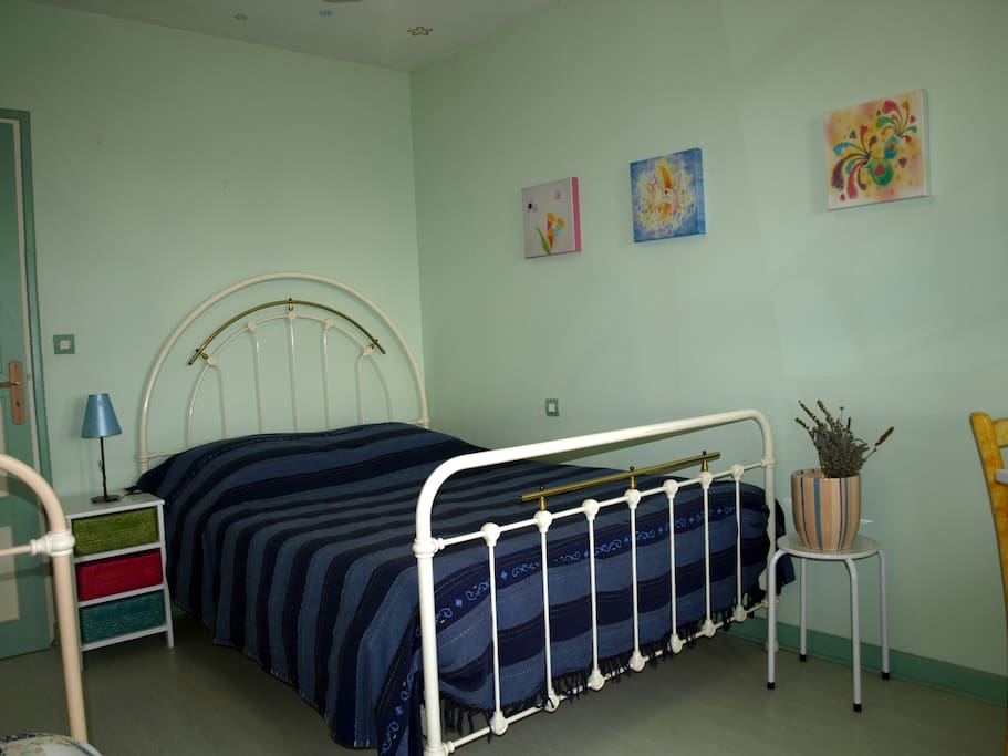chambre bleue avec un grand lit et un petit lit. table, chaises et placard intégré