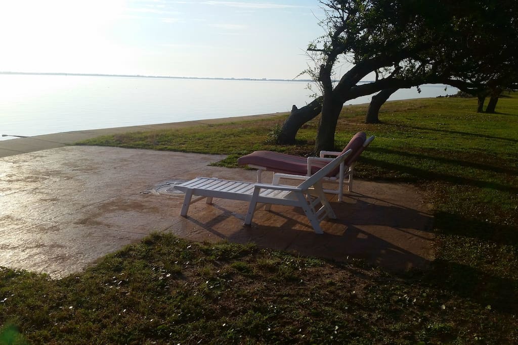 Patio with 2 lounge chairs and small table along the sound.