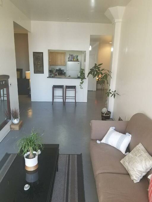 Daytime living room connected with a kitchen view.