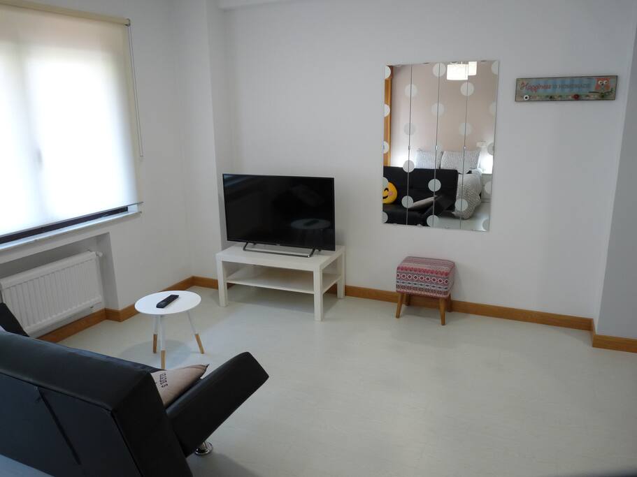 Salón con televisión 43", espejo y perchero.