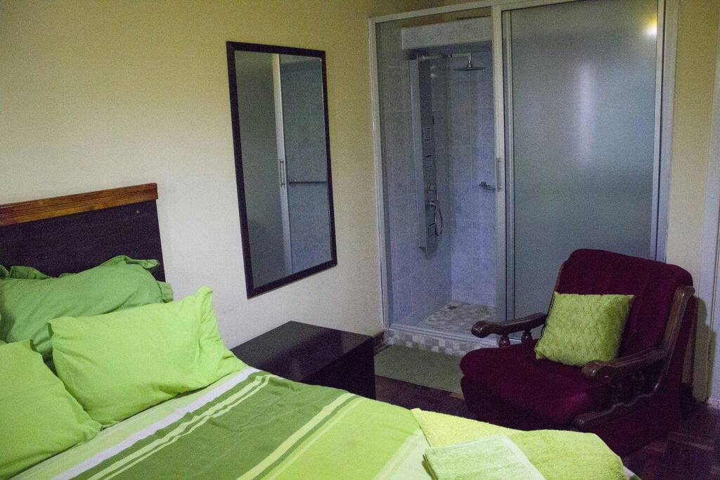 green bedroom with single couch and ensuite shower