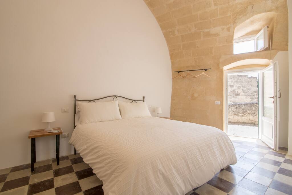 Camera con letto matrimoniale, dotata di finestre e porta finestra.