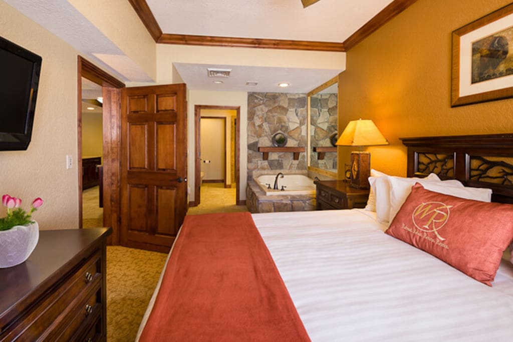 Master bedroom with king bed, large TV, ceiling fan and jetted tub