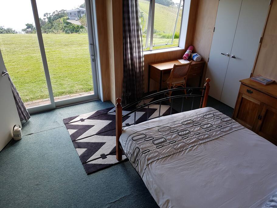 Queen bedroom. En-suite to left of frame. Sliding door opens onto grass lawn with panoramic view.