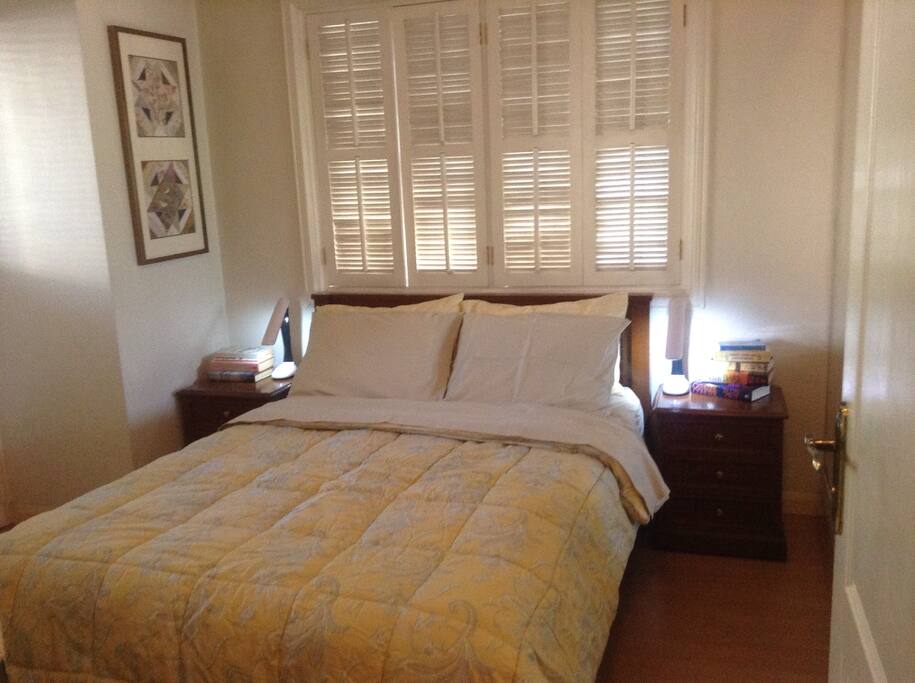 The Bedroom with a Queen bed. A sliding door opens to a porch that overlooks The Mind Museum, Shang Ri La Hotel at The Fort, and Bonifacio High Street shops and promenade.