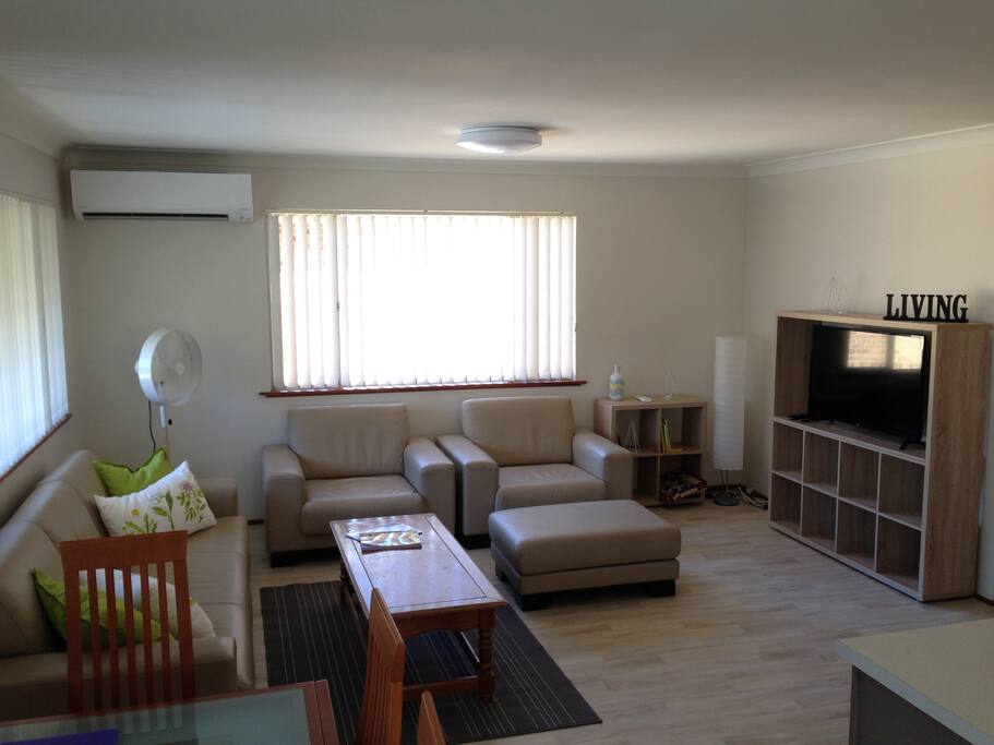 Air-conditioned Lounge room with King Furniture, large TV and some books.