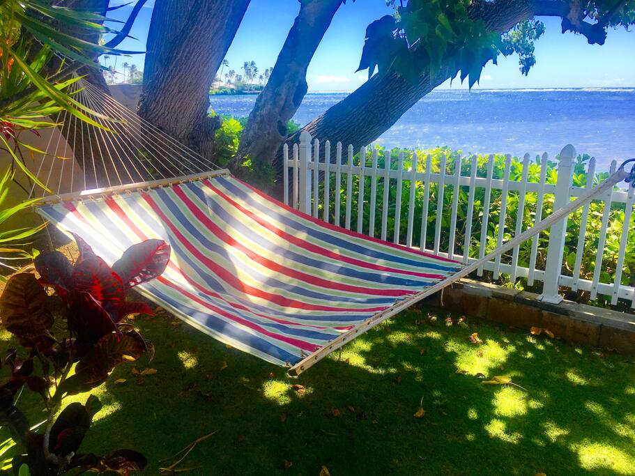 Hammock next to waves and under shade tree.