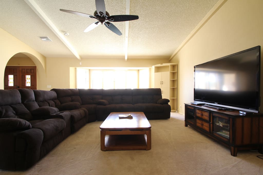 Living room area with two reclining couches one reclining chair and 70' cable TV and blu ray player