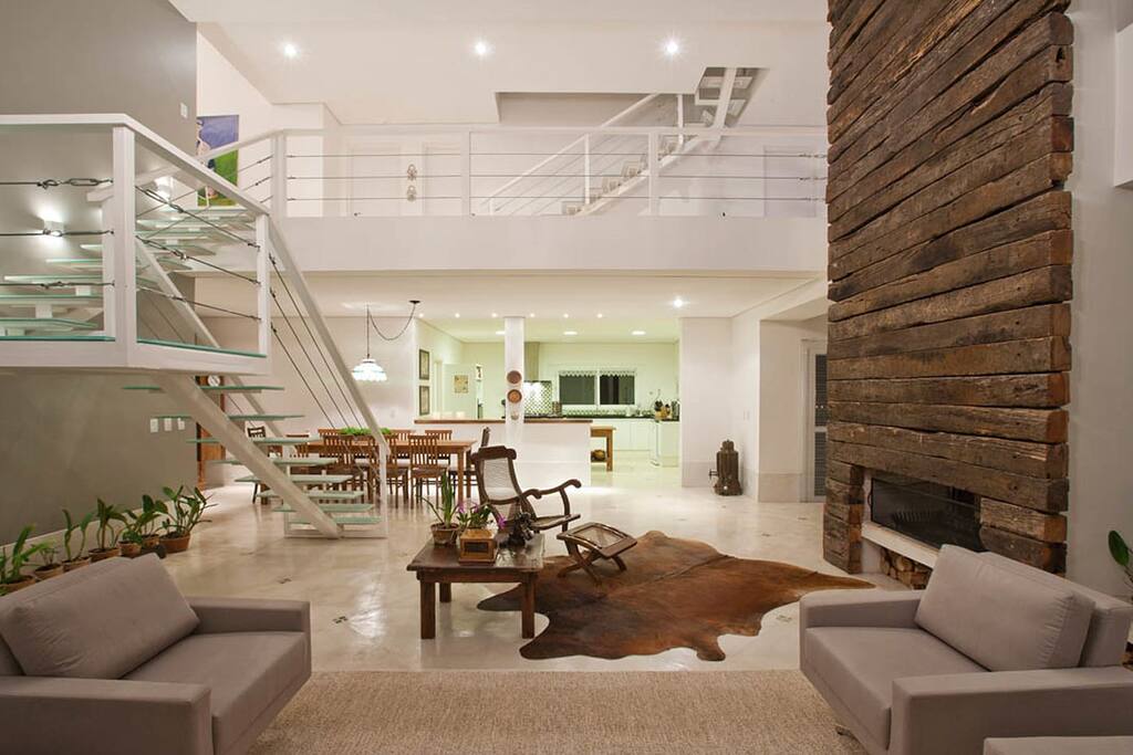 O living room integra todos os ambientes sociais, sala de estar, sala de jantar, home-theater e cozinha. Um dos destaques do ambiente é o volume revestido de dormentes que comporta três lareiras, que atendem ao living room e ao home-theater, no pavimento térreo, e à sala íntima, no pavimento superior. Outro destaque é a escada contemporânea feita de estrutura metálica e de vidro temperado.