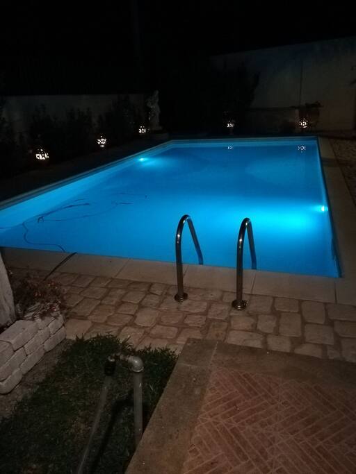 Veduta notturna giardino e piscina illuminata con luci a led colorate.