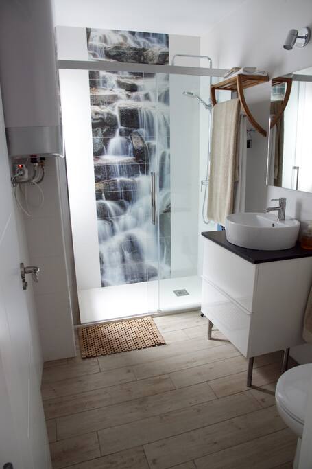 Coqueto baño con gran plato de ducha y mampara de cristal. Azulejos de diseño para disfrutar de una relajante ducha.