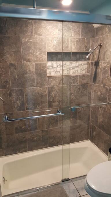 spacious shower with wall shower & ceiling rain shower in a unique sunken tub.