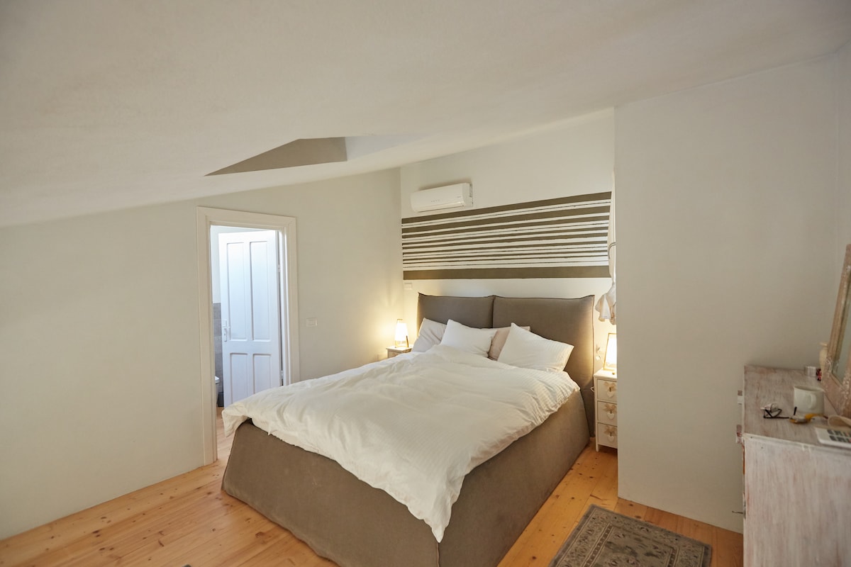 The bedroom has one comfortable bed (160x200) with a set of two duvets and four pillows. Left you see the door to the upper bathroom. Aircon is available in both rooms upstairs.