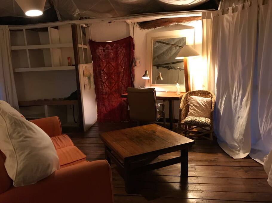 Inside sofa looking toward the bathroom and cupboard space and work desk with lantern. Curtains shut on front door.