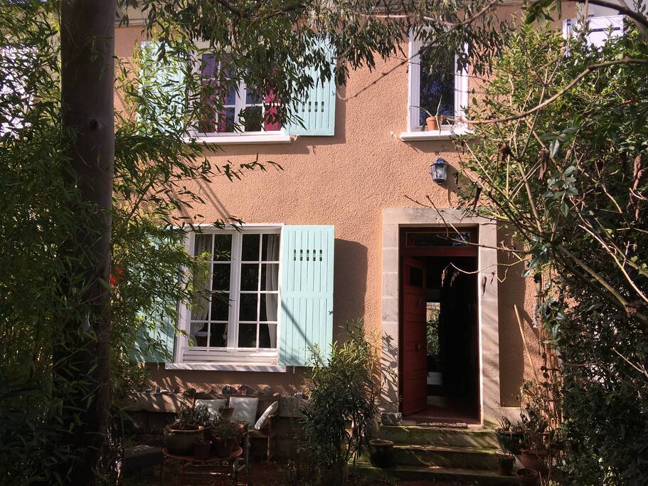 façade d'entrée séparée de la rue par un jardin où sont rangés les vélos