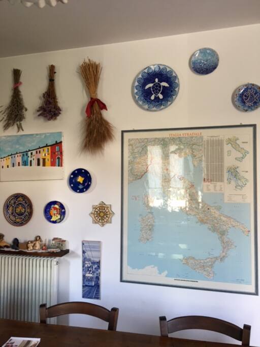 the wall with a map of Italy, some hanging dishes of Lampedusa and lavender , flowers and wheat crop in the field of my mother.