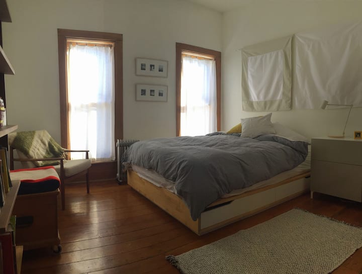Comfortable queen sized bed in a spacious, light filled bedroom.