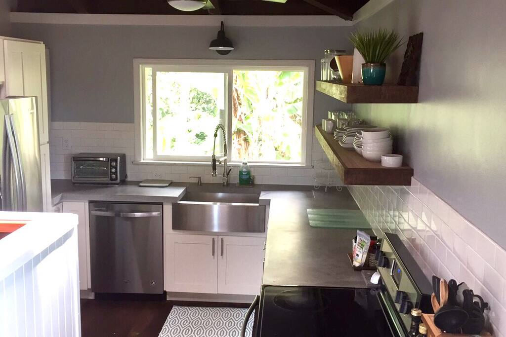 Newly updated Farmhouse style kitchen with stainless steal appliances & custom concrete countertops. Window Looks out to tropical plants.