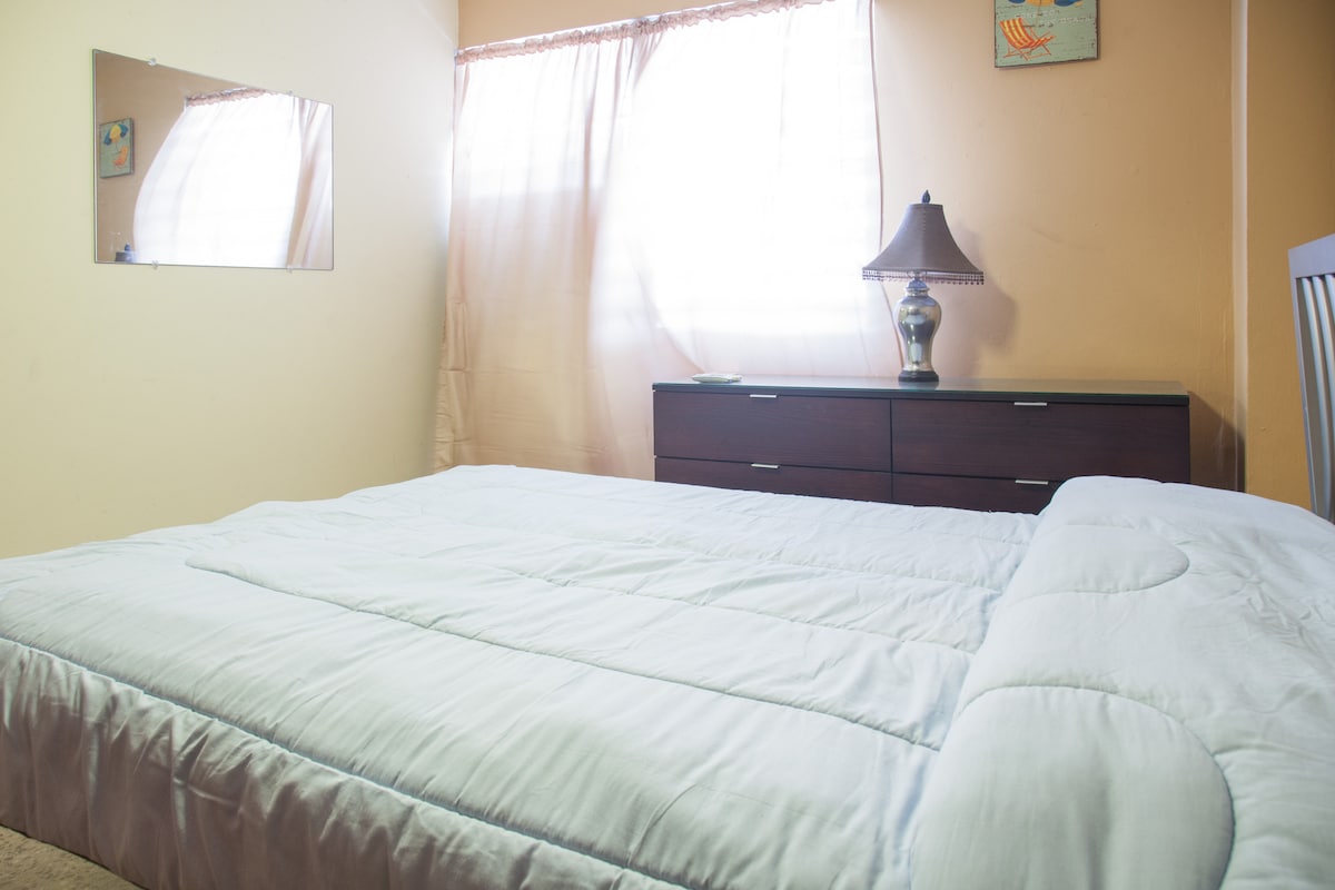 Dormitorio principal, con cama tamaño queen nueva, cómoda, aire acondicionado y ventilador de techo.