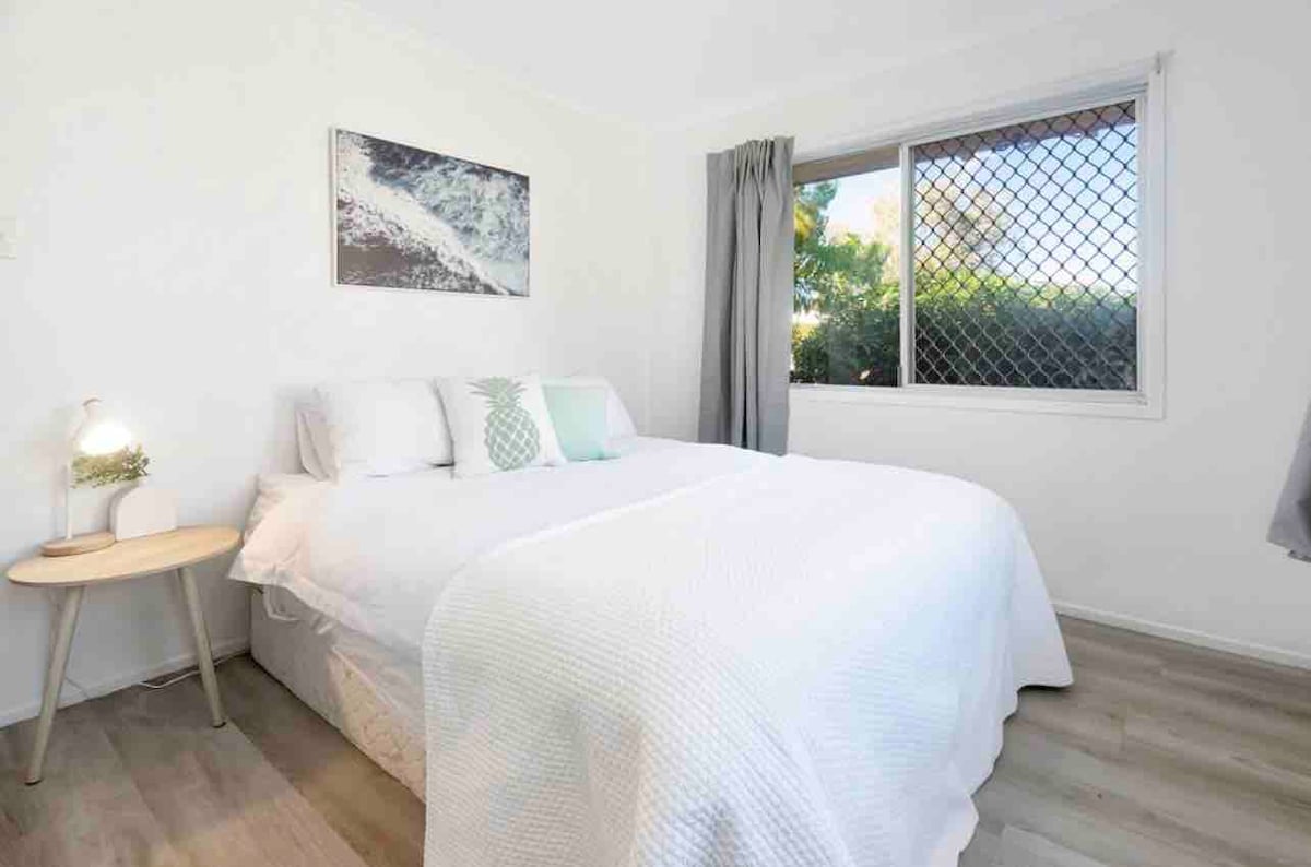 Esta habitación tiene una cama tamaño queen y un armario empotrado. Hay una mesa auxiliar de mano y una lámpara de mesa, y grandes ventanales a ambos lados con cortinas de bloqueo. Privacidad total con vallas altas de casas vecinas y un jardín.