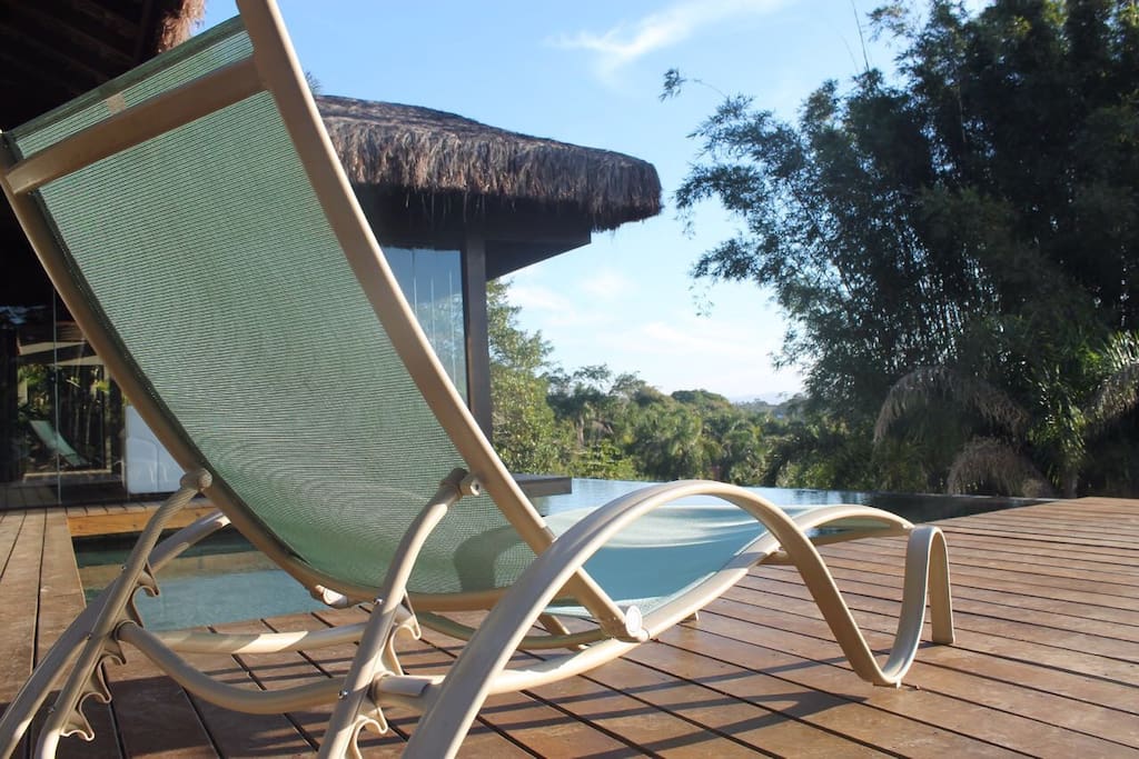 Área comum com piscina, deck, churrasqueira, sala de estar e banheiros.