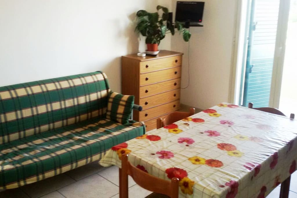 soggiorno con divano letto matrimoniale e angolo cottura