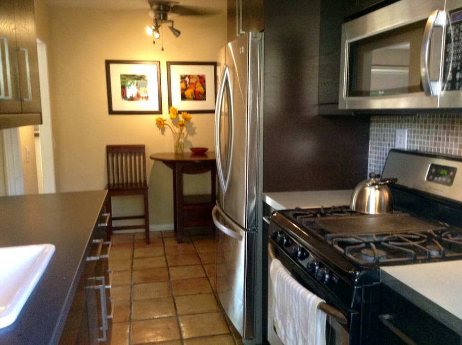 Galley kitchen with gas stove, microwave and french door refrigerator with ice maker