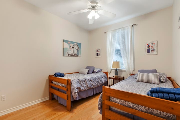 Bedroom #3 with two twin beds, a small nightstand, a lamp, and a ceiling fan