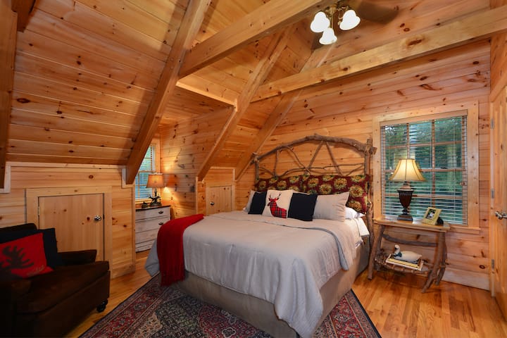 Sovrum på övervåningen med dubbelsäng, katedraltak, takfläkt och platt-TV.