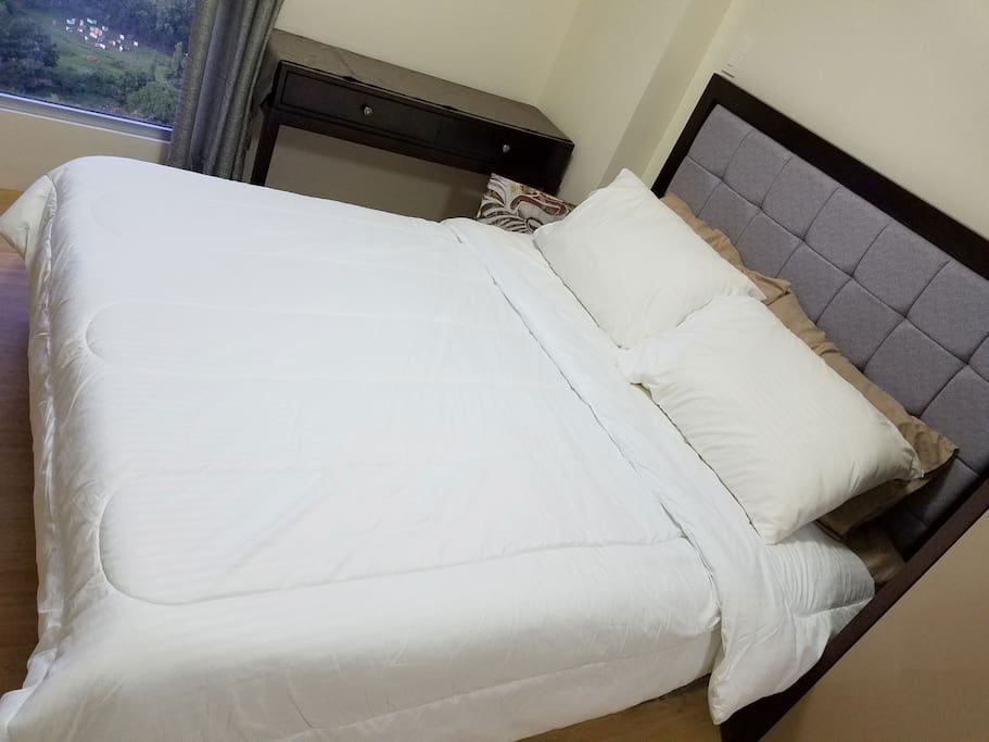 Queen sized bed with headboard, four pillows for convenience, comforters