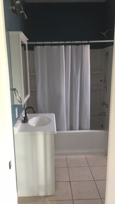 Full bathroom on ground floor connecting to main living room with shower/tub