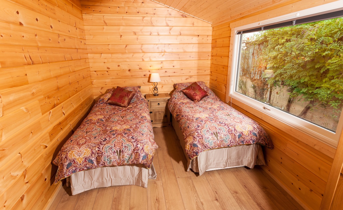 Habitación con dos camas y armario, cómoda y mesita de noche con lámpara