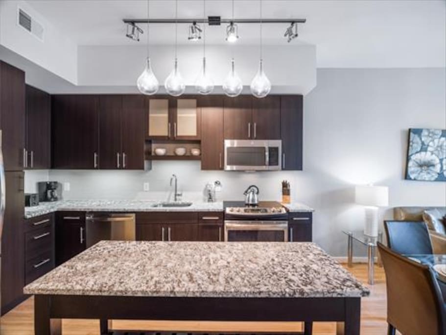 Fully equipped kitchen with stainless steel appliances, pots, pans, and dishes