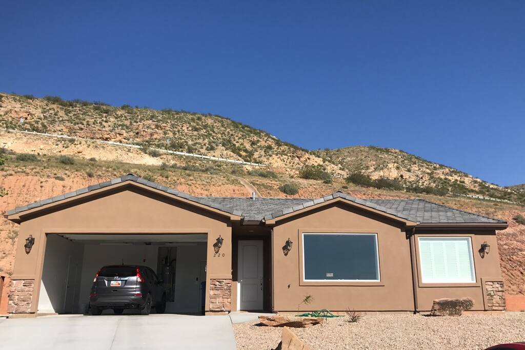 Front view of the house with little hill behind the property