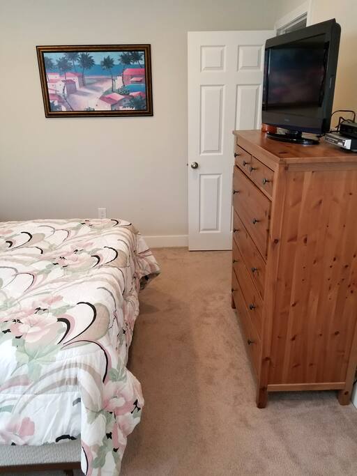 TV with cable and dresser in bedroom.