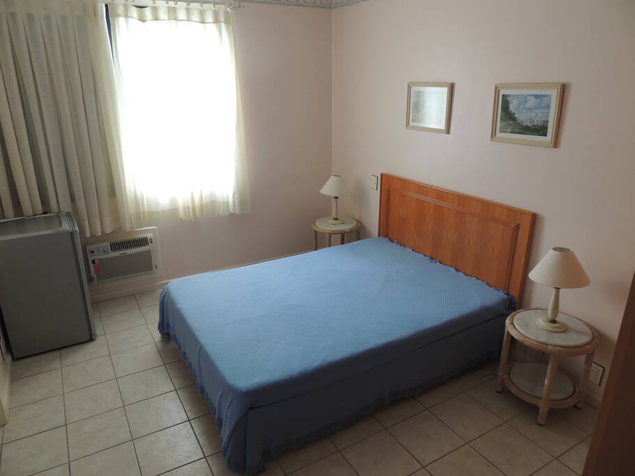 Suíte casal com ar condicionado e ventilador de teto.