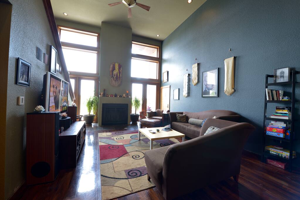 Large living room with fireplace, two story windows, TV and a variety of books