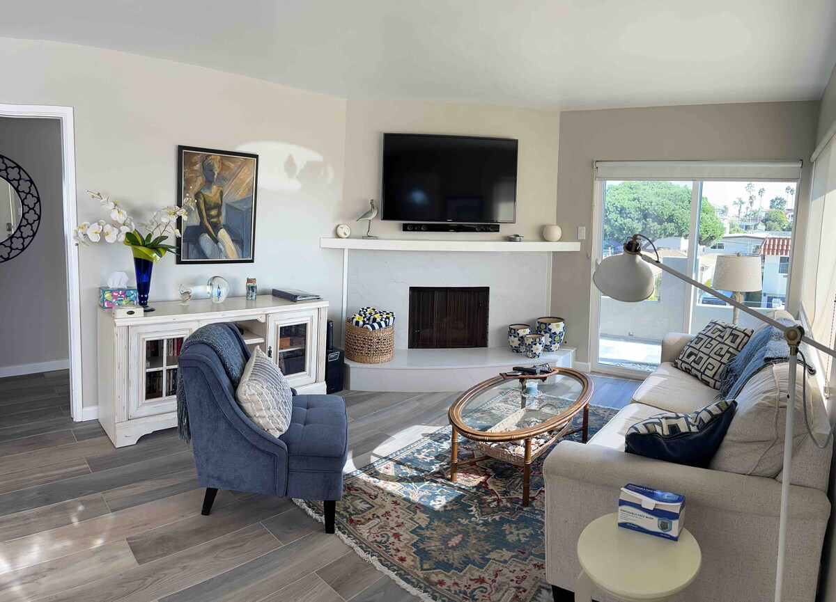 غرفة المعيشة المعاد تشكيلها 10/2023 مع تلفزيون ذكي 60بوصة وإطلالة جزئية على المحيط.  أرضيات بلاط جديدة تشبه الخشب.  يفتح شريط التمرير على سطح السفينة مع الأثاث.  مكان رائع لتناول قهوة الصباح أو لمشاهدة غروب الشمس.