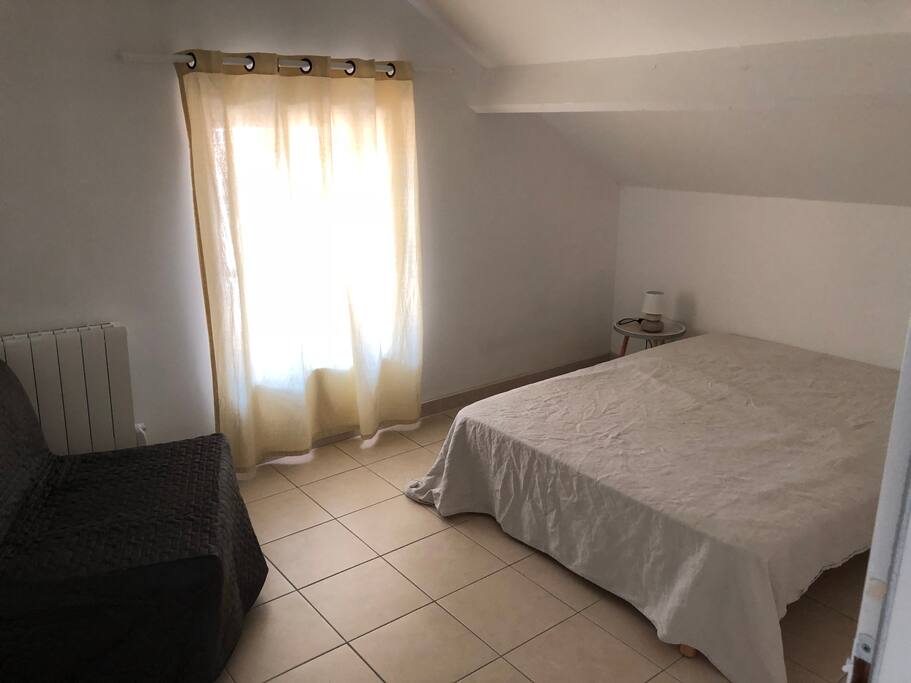 Chambre avec lit double de 140 et chauffeuse à latte.