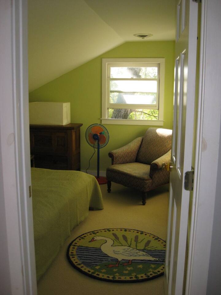 Cozy carpeted green colored bedroom with double- sizes futon bed off wide spacious hallway. 