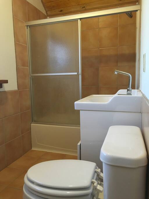 Bathroom with beautiful second story views of the garden, vanity sink and mirror, medium sized tub.