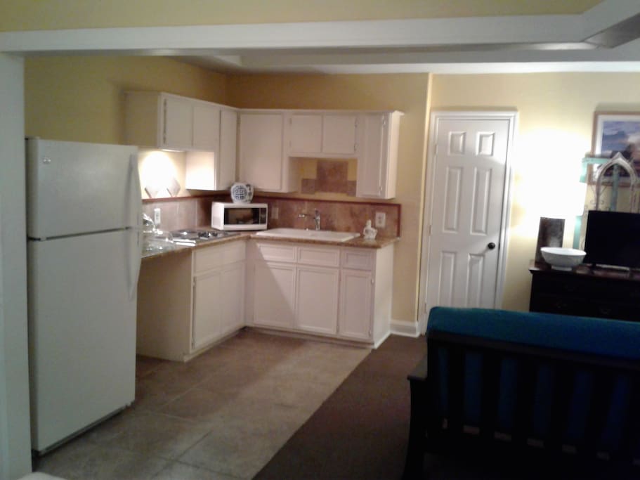 Kitchen with full size refrigerator and electric stove top, microwave and Kuerig coffee machine.